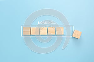 Showing loading bar with wood cube on blue background. Wooden blocks with the word LOADING in loading bar progress