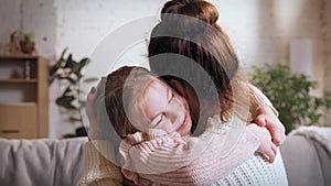 Showing love and care. Young woman, mother hugging her little smiling daughter. Spending time at home on daytime