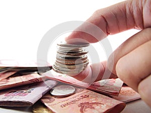 Showing pile of coins on finger on banknotes