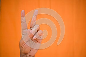 Showing victory sign against orange background