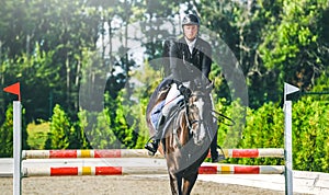 Showjumping competition, bay horse and rider in black uniform performing jump over the bridle.