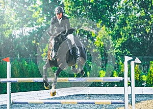 Showjumping competition, bay horse and rider in black uniform performing jump over the bridle.