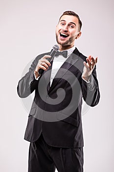 The Showman interviewer with emotions. Young elegant man holding microphone against white background.