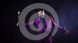 Showman. Young male entertainer, presenter or actor on stage. The guy in the purple camisole and the cylinder.
