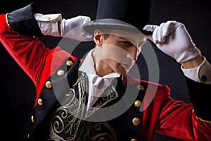 Showman. Young male entertainer, presenter or actor on stage. The guy in the red camisole and the cylinder.