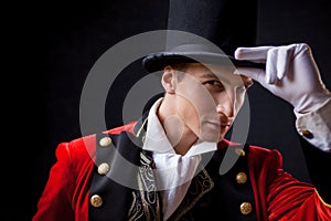 Showman. Young male entertainer, presenter or actor on stage. The guy in the red camisole and the cylinder.