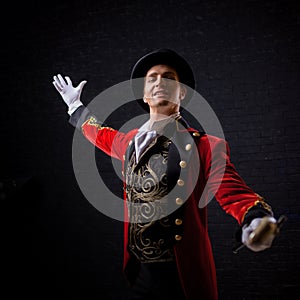 Showman. Young male entertainer, presenter or actor on stage. The guy in the red camisole and the cylinder.