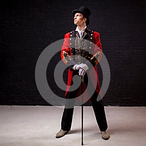 Showman. Young male entertainer, presenter or actor on stage. The guy in the red camisole and the cylinder.