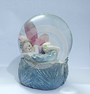 Showpiece of angel with wings sleeping on flower inside a glass dome photo