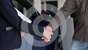 Showroom car, sales manager shake hands with buyer owner Spbi. Close up agent hold clipboard