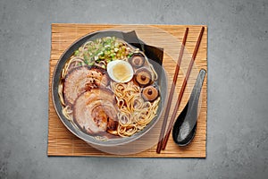 A Shoyu Ramen in gray bowl on concrete table top. Japanese cuisine meat noodle soup with chashu pork. Asian food