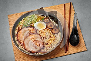 A Shoyu Ramen in gray bowl on concrete table top. Japanese cuisine meat noodle soup with chashu pork. Asian food