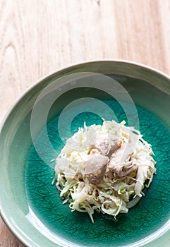 Shredded cabbagefried pork /Green circular plate placed on a w