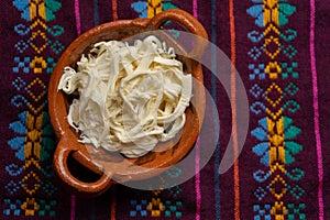 Shredded Oaxaca cheese also called quesillo on rustic background. Mexican food photo