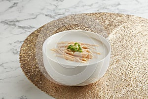 Shredded Steamed Chicken Congee served in a bowl side view on grey marble background traditional vietnamese food