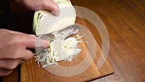 Shredding of white cabbage head on the wooden cutting board