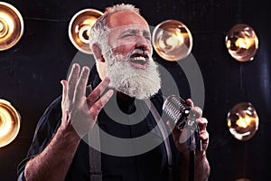 A shrewd look of emotional gray bearded man singing in a silver