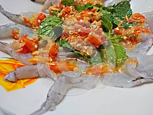 Shrimp in fish sauce and topped with spicy dipping sauce and  mint leaves