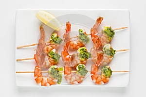 Shrimp kebab served with sauce and lemon top view on a white background. Prawn starter on skewers top view