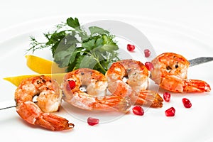 Shrimp kebab skewer served with lemon and parsley on a white background. Prawn starter on a skewer close up