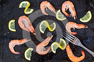 shrimp, lemon and sea salt with fork on a dark black background