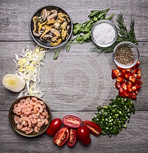 Shrimp and mussels in metal bowls with spices onion pepper tomatoes and herbs lined circle frame wooden background top view