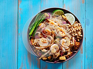 Shrimp pad thai on plate in flat lay composition