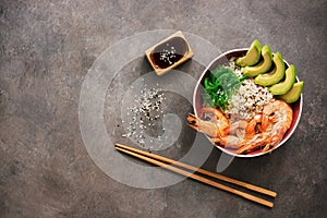 Shrimp poke bowl, rice, avocado, chuka, soy sauce and sesame on a dark rustic background. Top view, flat lay, copy space