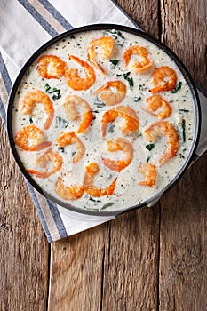 Shrimp with spinach and parmesan in cream sauce close-up on a pl