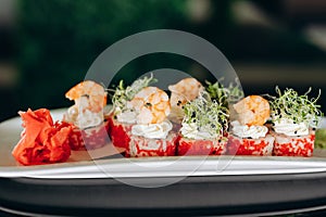 Shrimp sushi on a white plate decorated with caviar, greens and shrimp