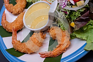 Shrimp tempura and salad of fresh vegetables close-up on a plate on black background. horizontal view from above