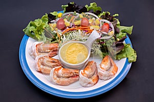 Shrimpand salad of fresh vegetables close-up on a plate on black background. horizontal view from above