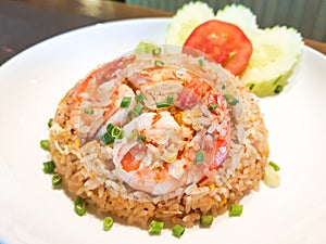 Shrimps fat fried rice garnish with slice cucumbers and tomato on top with shrimps