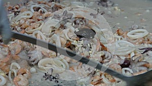 Shrimps, mussles and onion are cooked and mixed on a metallic tray