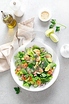 Shrimps salad with green lettuce, cucumbers and avocado, dressed with lime juice, healthy and tasty food, top view