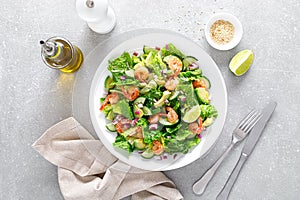 Shrimps salad with green lettuce, cucumbers and avocado, dressed with lime juice, healthy and tasty food, top view