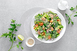 Shrimps salad with green lettuce, cucumbers and avocado, dressed with lime juice, healthy and tasty food, top view