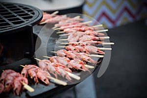 Shrimps on wooden skewers on a grill