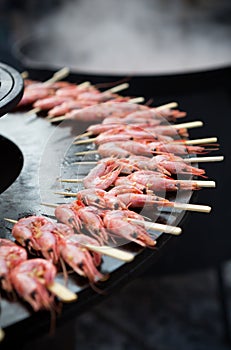 Shrimps on wooden skewers on a grill