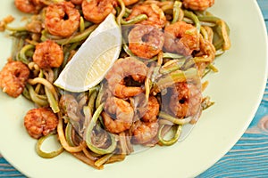 Shrimps and zucchini cut as noodles in green plate, close-up