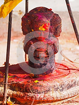 Shrine covered in vermillion to worship Goddess Kali. Red pigment powder on statue in Dhulikhel, Nepal