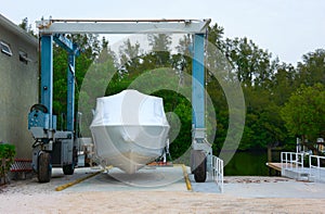 Shrink wrapped boat strapped on a mobile lift in a marina preparing it for winter storage or shipment