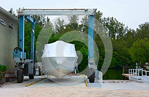 Shrink wrapped boat strapped on a mobile lift in a marina preparing it for winter storage or shipment photo