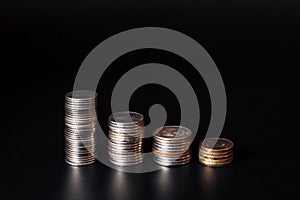 Shrinking stacks of coins on a black background