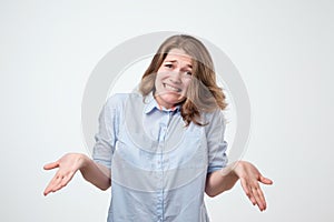 Shrugging european woman wearing blue shirt in doubt doing shrug