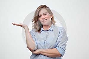 Shrugging european woman wearing blue shirt in doubt doing shrug