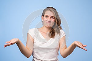 Shrugging european woman wearing blue shirt in doubt doing shrug