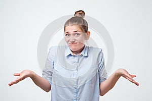 Shrugging european woman wearing blue shirt in doubt doing shrug photo