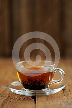 Shu puerh tea brewed steaming in glass cup on wooden background