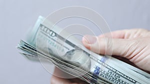shuffling stack pack of hundred 100 dollar bills on light grey background